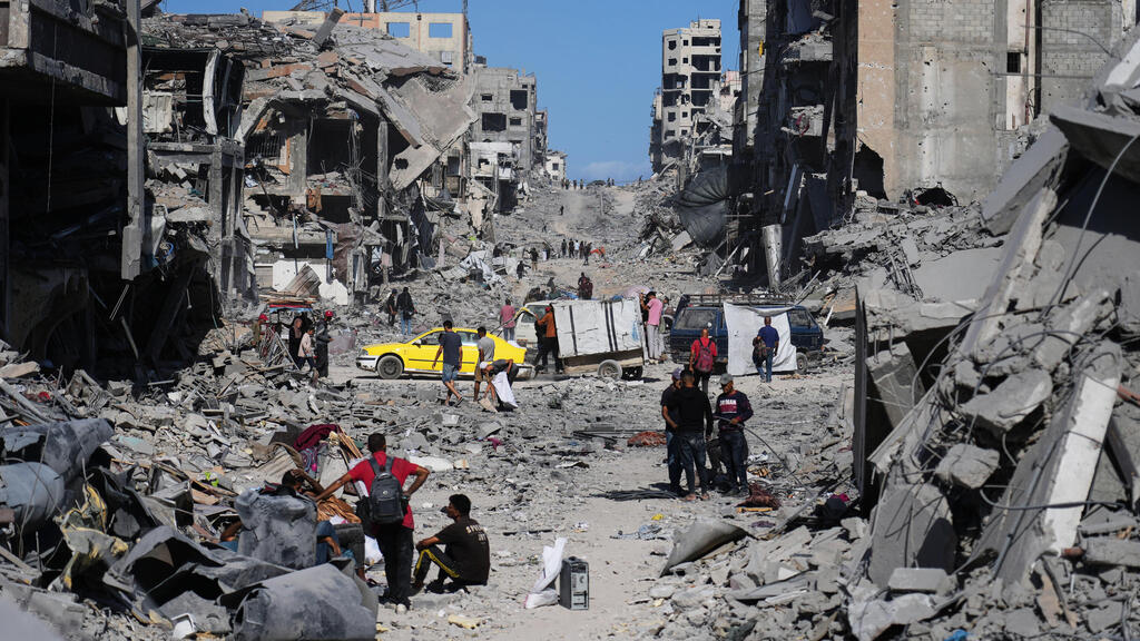 Разрушения в Газе (Фото: AP Photo/Abdel Kareem Hana) עקורים פלסטינים חולפים על פני הריסות