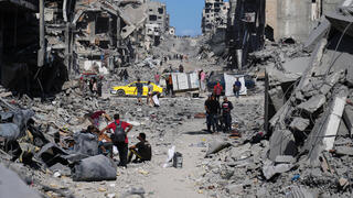 עקורים פלסטינים חולפים על פני הריסות