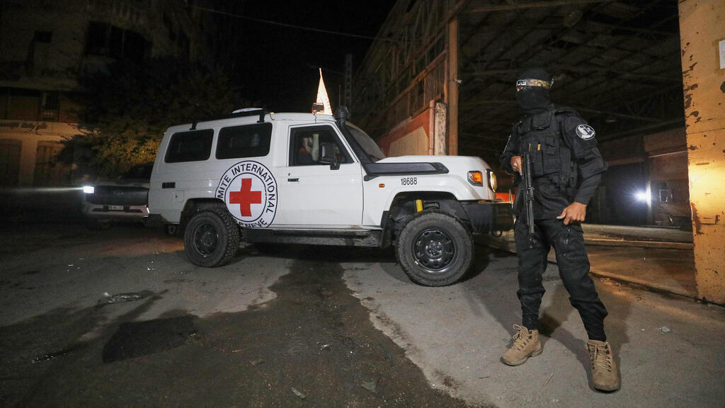 A Hamas terrorists near a Red Cross vehicle in past hostage hand over (Photo: AP/ Yousef Al Zanoun) העברת הגופות לצלב האדום החלה