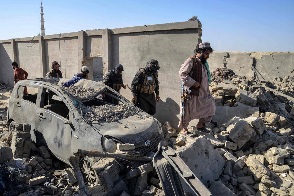 Taliban security personnel walk past a damaged car in Kandahar province a day after the cross-border clashes between Afghanistan and Pakistan.