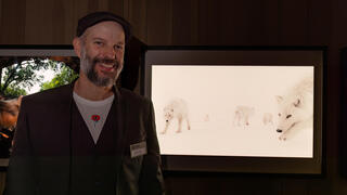 צלם הטבע עמית אשל ברקע תמונת הזאבים הארקטיים שצילם באי אלסמיר