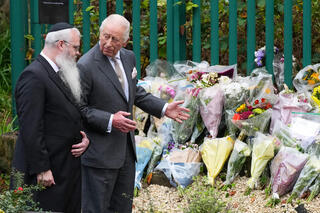 Rabbi Daniel Walker and King Charles III view floral tributes during a visit to Heaton Park Hebrew Congregation Synagogue on October 20, 2025 in Manchester, England