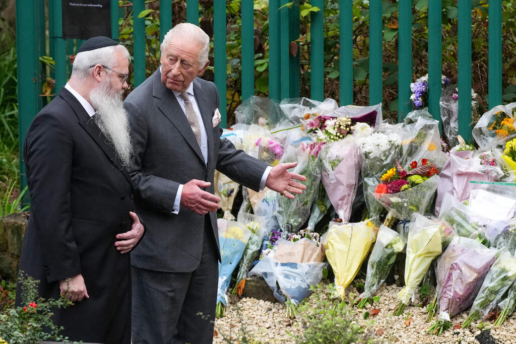Rabbi Daniel Walker and King Charles III view floral tributes during a visit to Heaton Park Hebrew Congregation Synagogue on October 20, 2025 in Manchester, England