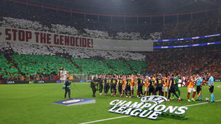 אוהדי גלאטסראיי עם תפאורה של דגל פלסטין ושלט נגד ישראל