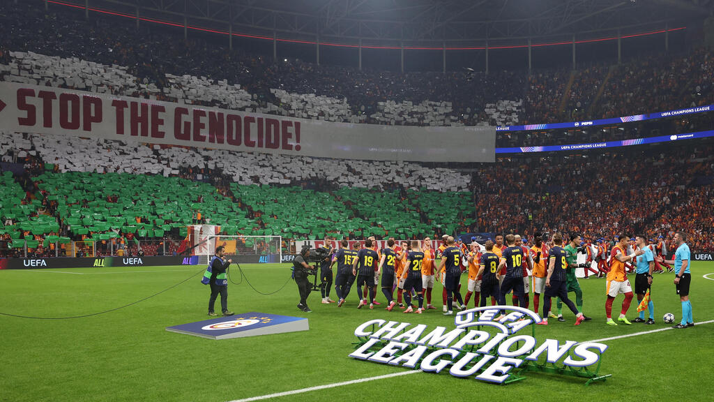 אוהדי גלאטסראיי עם תפאורה של דגל פלסטין ושלט נגד ישראל