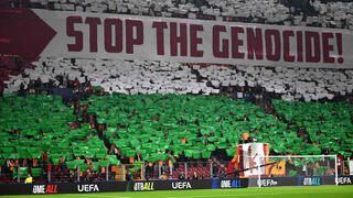 אוהדי גלאטסראיי עם תפאורה של דגל פלסטין ושלט נגד ישראל