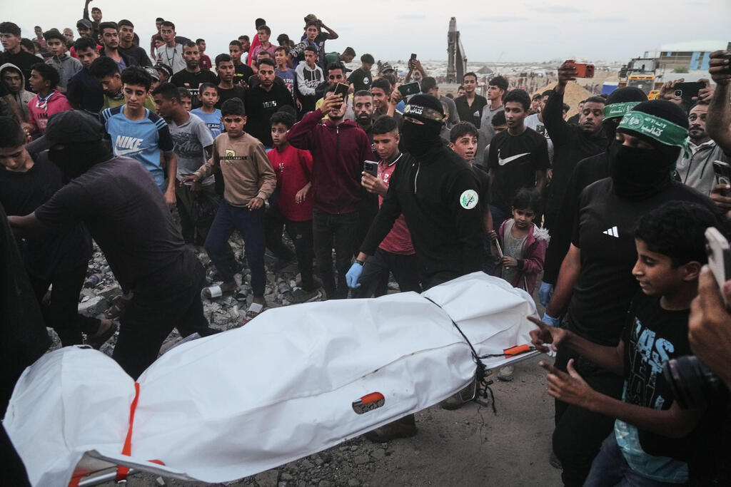 Photo: AP Photo/Jehad Alshrafi מחבלי חמאס מחלצים לכאורה שרידים של חלל חטוף בשכונת חמד חאן יונס רצועת עזה