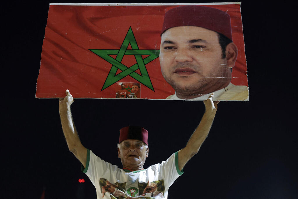 A Moroccan celebrates with a photo of the king (Photo: Abdel Majid BZIOUAT / AFP) מרוקו חגיגה חגיגות החלטה ב מועצת הביטחון האו"ם או"ם ריבונות סהרה המערבית