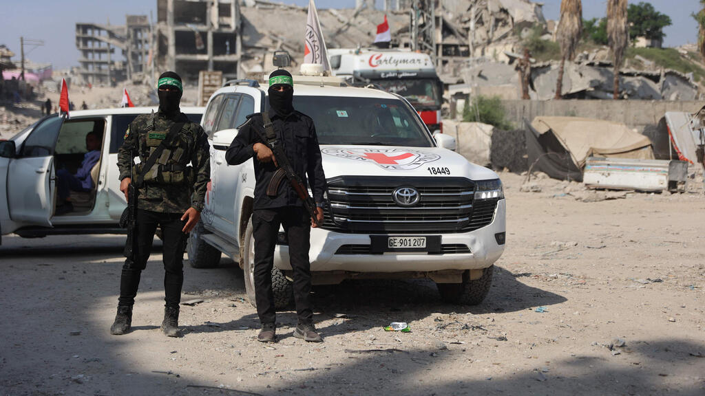 Hamas terrorists next to Red Cross vehicles (Photo: Omar al-Qattaa/ AFP) חיפושים אחרי חללים חטופים בעזה