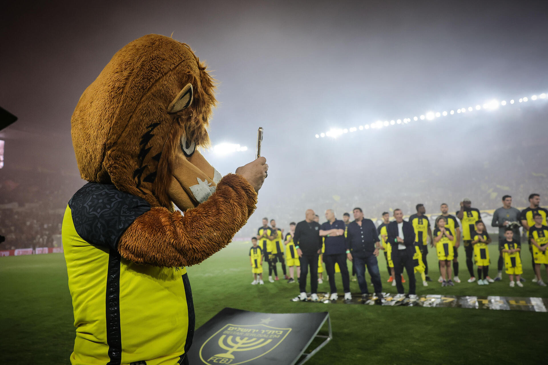 הקמע של בית"ר ירושלים מצלם את הטקס בטלפון, לפני פתיחת המשחק  