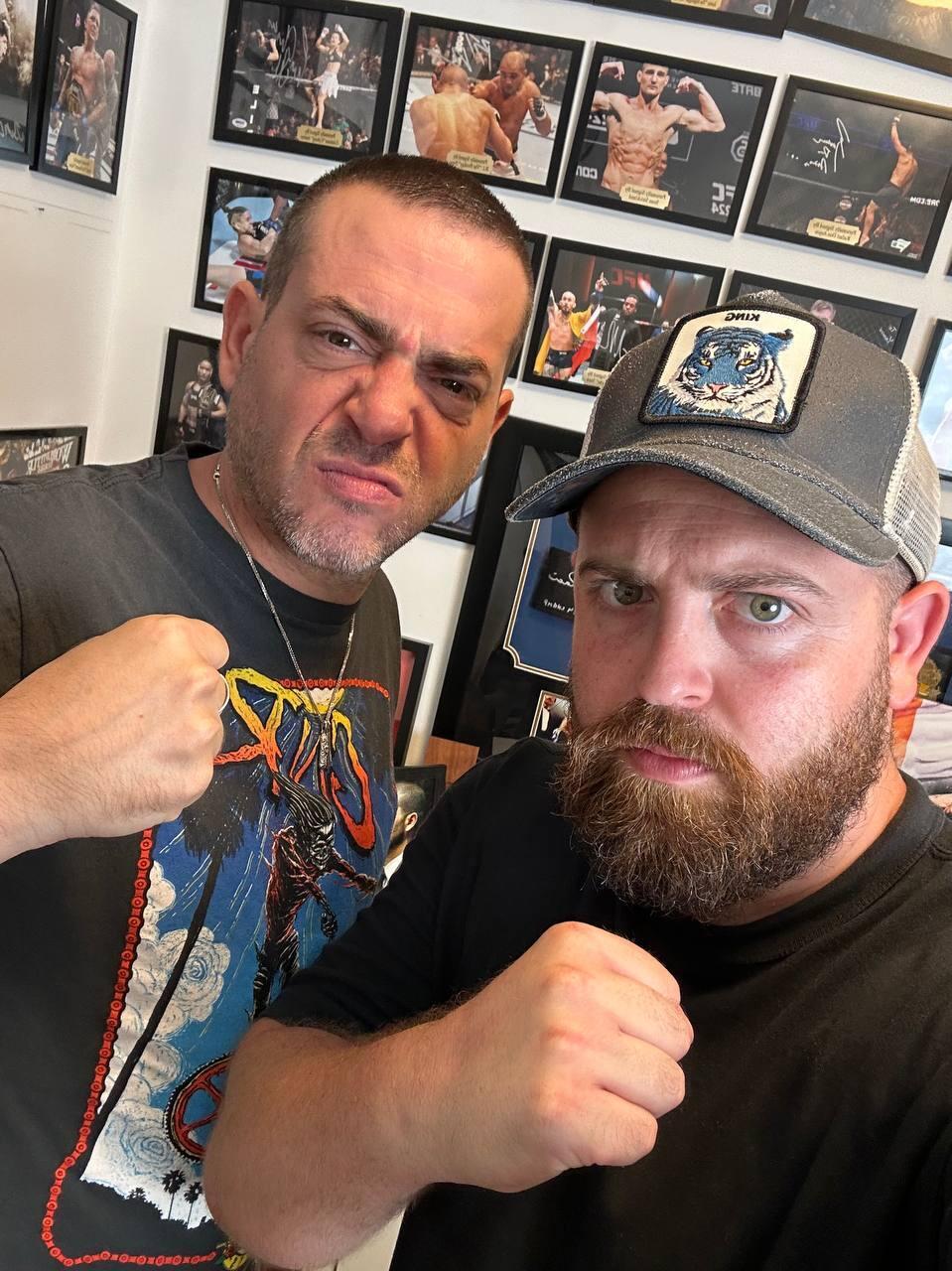 Yaniv Kaminski, left, poses with Bar Gindy in front of a wall of autographed UFC memorabilia at Kaminski’s personal collection room (Photo: Bar Gindy) Yaniv Kaminski, left, poses with Bar Gindy in front of a wall of autographed UFC memorabilia at Kaminski’s personal collection room