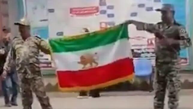 אנשים במדי צבא שלטענת איראן הם מתחזים מניפים את דגל איראן הישן מלפני המהפכה האיסלאמית ב מטרו ב טהרן