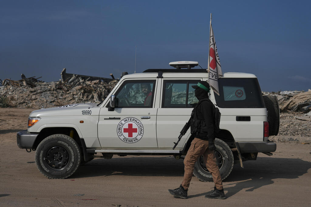 A Hamas gunman stands beside an International Committee of the Red Cross vehicle as Red Cross teams work to locate the bodies of hostages in eastern Gaza, Nov. 13, 2025 (Photo: AP Photo/Jehand Alshrafi) חמאס והצלב האדום פועלים לאיתור חטופים חללים במזרח העיר עזה