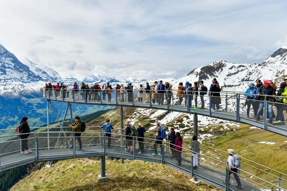Смотровая площадка в Швейцарии (Фото: i viewfinder, shutterstock) תיירים בנקודת תצפית בגרינדלוולד, שווייץ