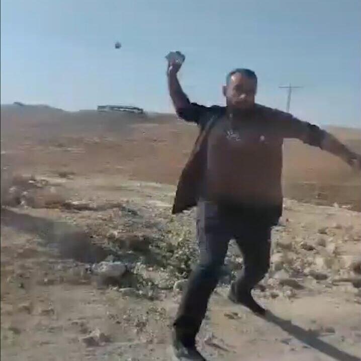 An unidentified Palesitnian man throws a rock at a car in the South Hebron Hills area פלסטיני תוקף באבן מתיישב באזור הר חברון