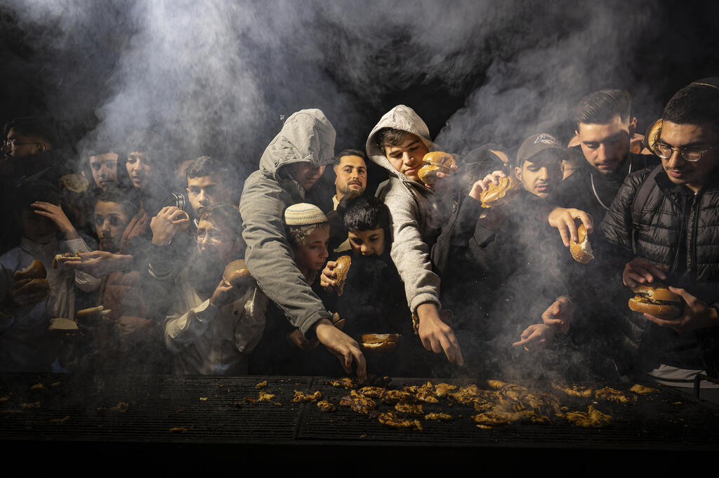 Worshippers gather at a festive barbecue during the annual hilula (commemoration) for the Baba Sali, a venerated Moroccan-Jewish rabbi (Netivot, February 1, 2025) (Photo: Smadar Ilutowich ) גברים וילדים מצטופפים ליד מנגל סעודת מצווה בעת ההילולה השנתית לכבוד הבאבא סאלי. נתיבות, 1 בפברואר 2025