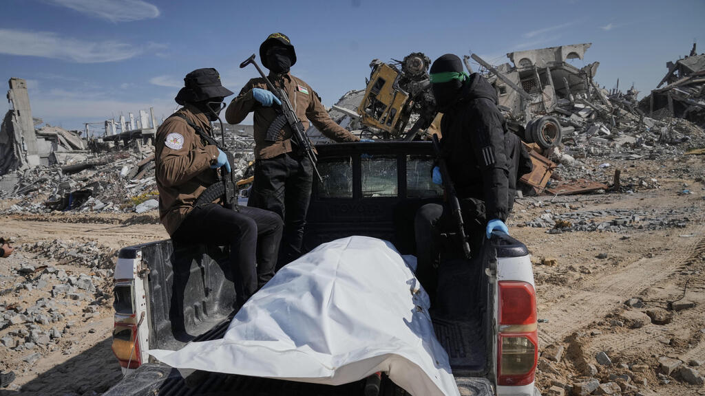 Боевики ХАМАСа с телом, обнаруженным в Газе (Фото: AP Photo/Jehad Alshrafi) מחבלי חמאס טוענים כי איתרו גופת חלל חטוף