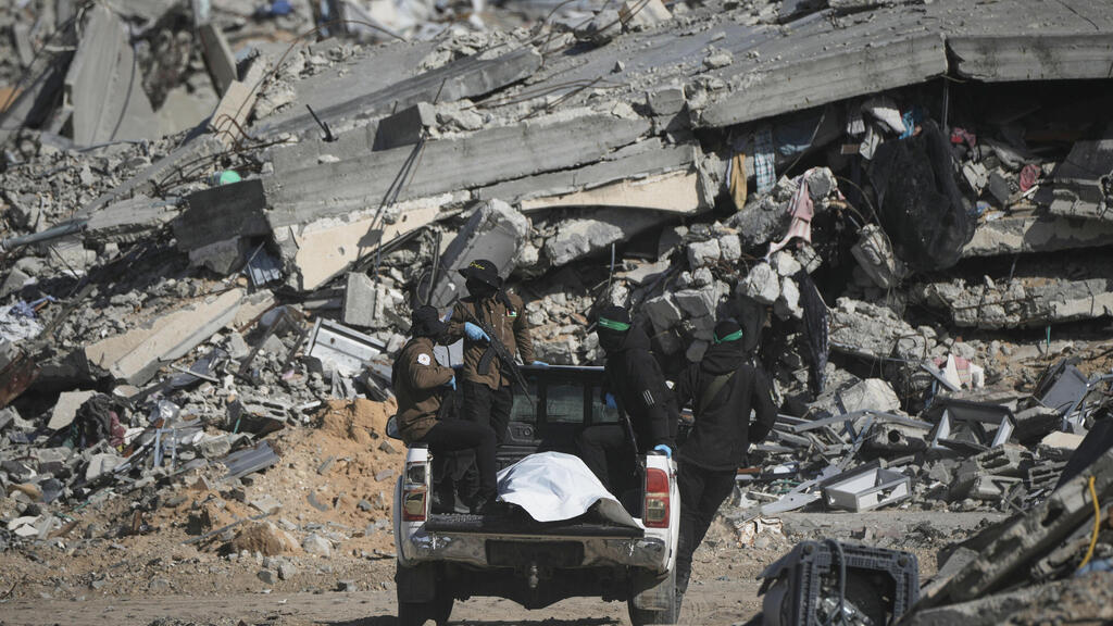 Террористы с телом, обнаруженном на севере Газы (Фото: AP Photo/Jehad Alshrafi) מחבלי חמאס טוענים כי איתרו גופת חלל חטוף