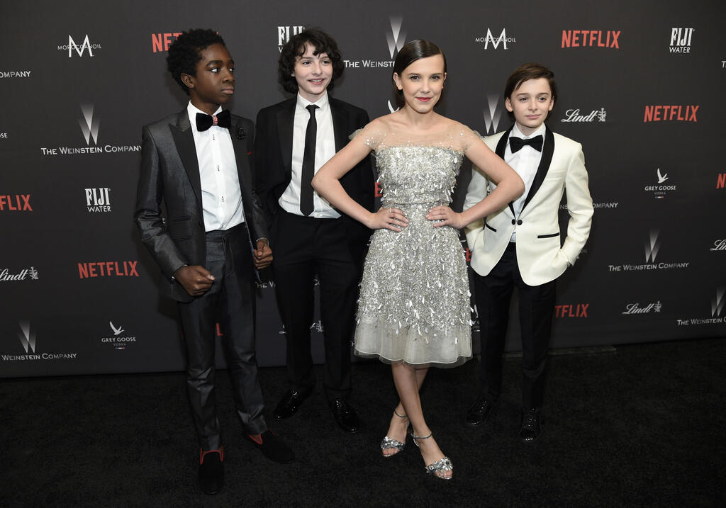 Jenny Packham dress; with 'Stranger Things' stars Noah Schnapp, Finn Wolfhard and Caleb McLaughlin on the red carpet, 2017 (Photo: Chris Pizzello/Invision/AP) מילי בובי בראון, נואה שנאפ, פין וולפהארד וקיילב מקלאפלין על השטיח האדום, 2017