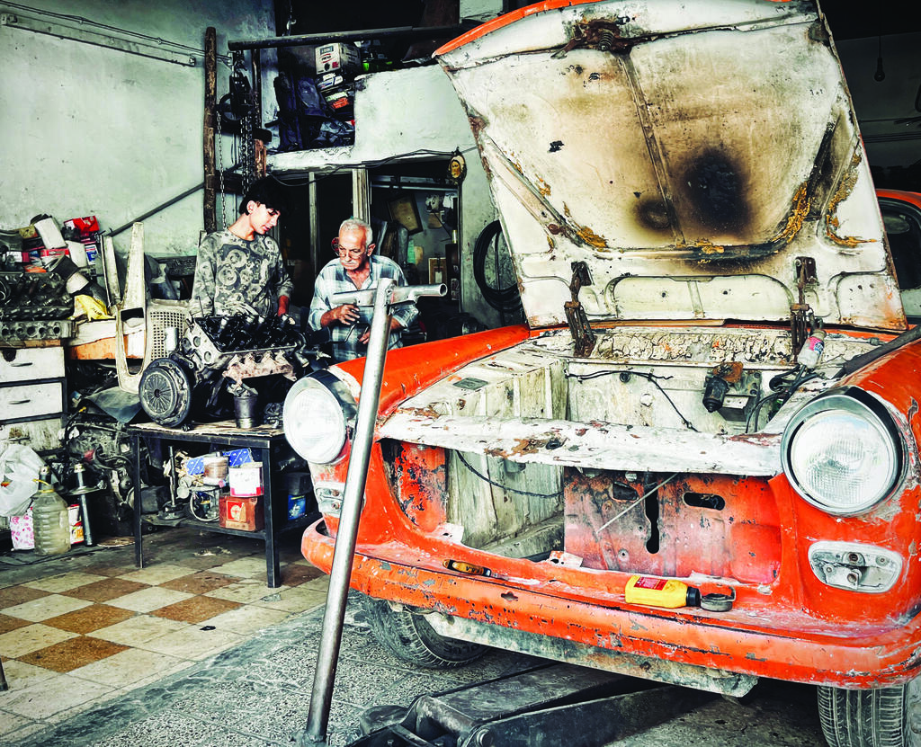 A mechanic and his assistant work on an engine in a small garage in Damascus. Many residents say rebuilding their lives has proved harder than surviving the war itself 