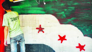 A man paints the Syrian opposition flag on a shopfront shutter in Damascus. Despite the government’s hold on the capital, signs of dissent still surface as residents adjust to political uncertainty after Bashar Assad’s departure 