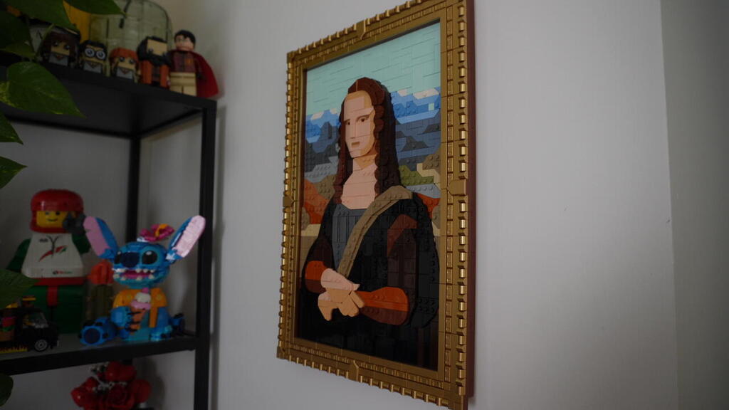 A framed Lego mosaic resembling the Mona Lisa hangs on a wall beside shelves filled with Lego figures and models at the home of collector Gal Zahavi 