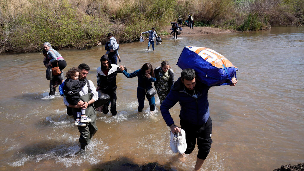 Syrian Alawite families who fled the clashes in Syria carry their luggage as they cross a river marking the border between Syria and northern Lebanon (Photo: AP) Syria Alawite women