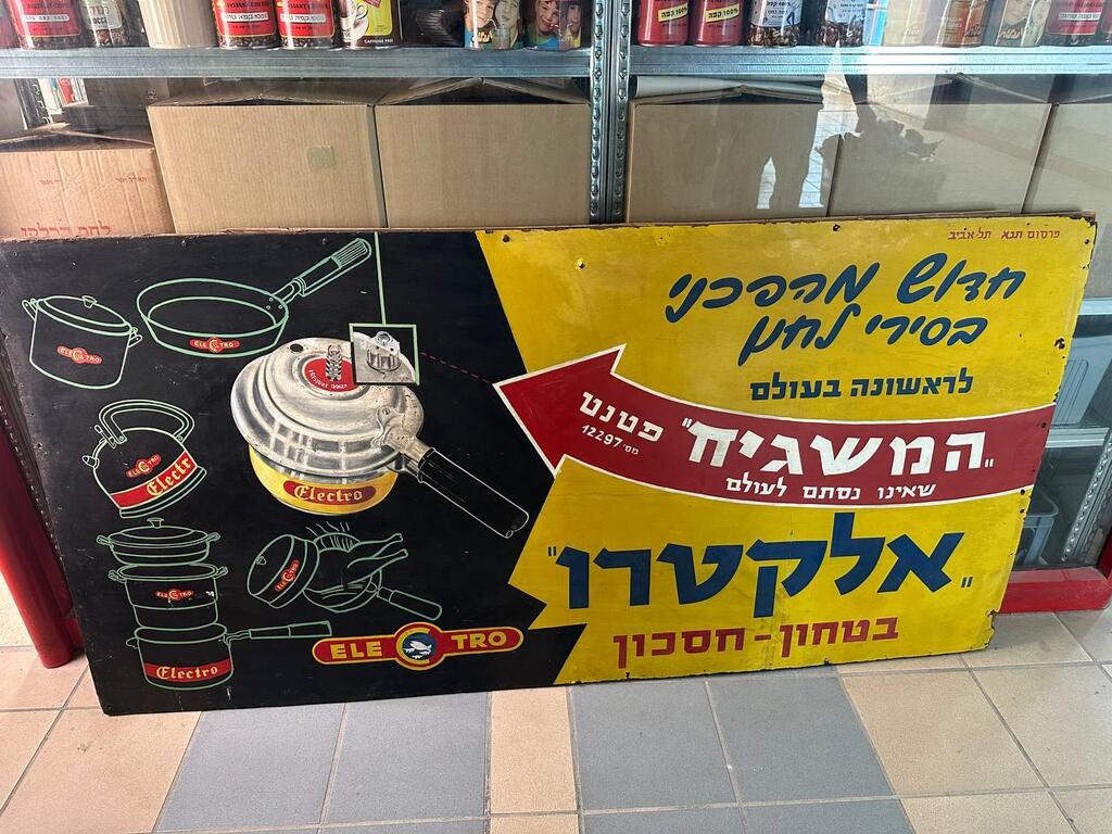 A vintage advertising sign for Electro cookware and pressure cookers, one of the many preserved items in Vital’s growing archive of everyday Israeli life. The sign, made of wood and tin, captures the era’s design and marketing language (Photo: Bar Gindy) A vintage advertising sign for Electro cookware and pressure cookers, one of the many preserved items in Vital’s growing archive of everyday Israeli life. The sign, made of wood and tin, captures the era’s design and marketing language