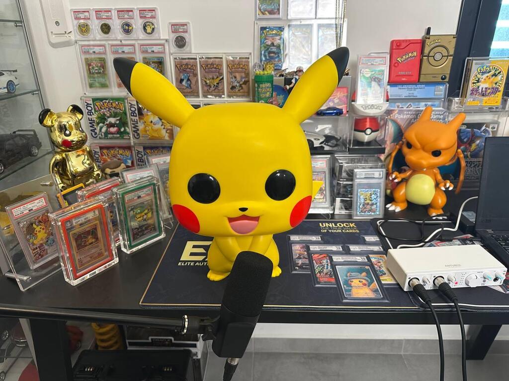 A large Pikachu figure sits on Dor’s desk, surrounded by rare graded Pokémon cards and collectibles 