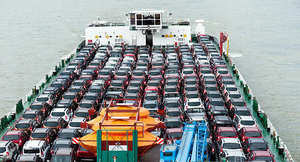 A vehicle carrier transports rows of new cars across open waters 
