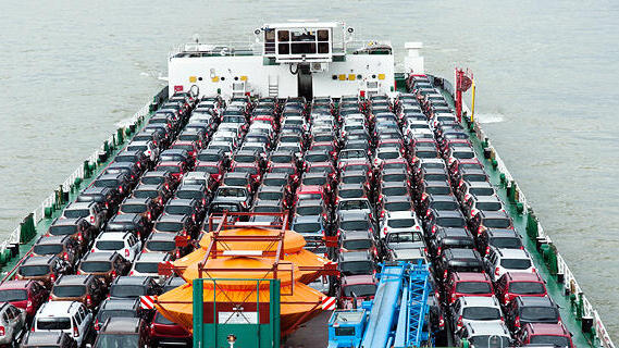 A vehicle carrier transports rows of new cars across open waters 