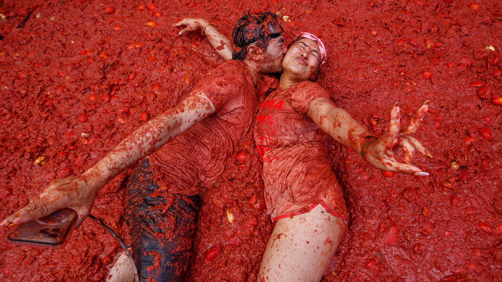 זוג מתנשק מעל שלולית עגבניות במהלך פסטיבל קרב העגבניות השנתי "טומטינה", בכפר בוניול סמוך לוולנסיה, ספרד, 27 באוגוסט 2025.