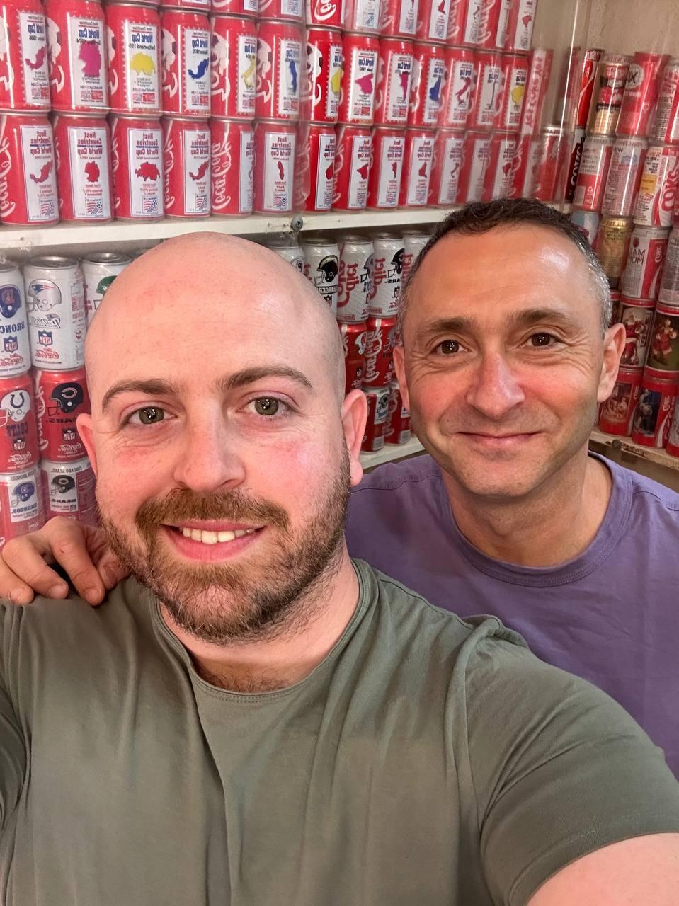 Bar Gindy, left, host of the People & Collectors podcast, poses with Coca-Cola can collector Ophir inside Ophir’s home collection room in Kibbutz Tzora 