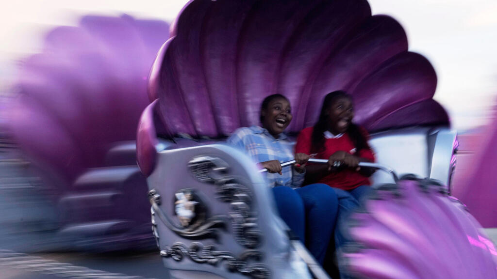 נערות מגיבות בזמן שהן עולות על המתקן “טמפסט” ביריד הפסחא ראנד ביוהנסבורג, דרום אפריקה, 19 באפריל 2025.