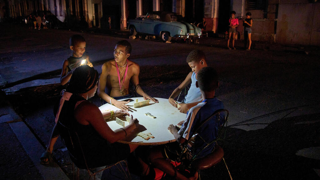 אנשים משחקים דומינו ברחוב במהלך הפסקת חשמל בהוואנה, 10 בספטמבר 2025.