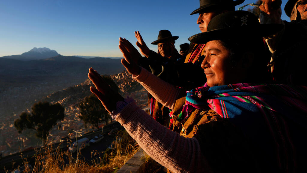 בני העם הילידי איימרה מרימים את ידיהם כדי לקלוט את קרני השמש הראשונות במסגרת חגיגות ראש השנה האנדי 5533, המציין את יום ההיפוך החורפי בחצי הכדור הדרומי, באל אלטו, בוליביה, 21 ביוני 2025.