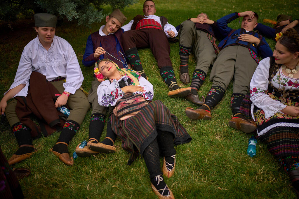 חברי להקה מסורתית מסרביה נחים בצל לקראת מצעד של הרכבים בינלאומיים ושל קבוצות אתניות מרומניה, המציגים תלבושות מסורתיות, ריקודים ושירים, בבוקרשט, רומניה, 21 ביוני 2025