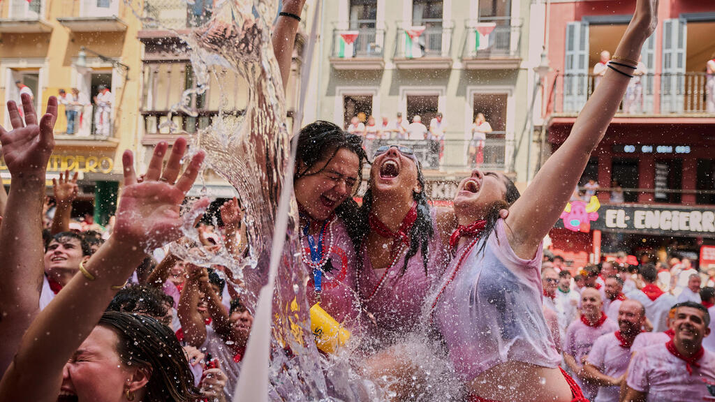 חוגגים מתקררים במים הנזרקים ממרפסות עם פתיחתם של תשעה ימים רצופים של חגיגות, במסגרת פסטיבל ריצת השוורים המפורסם בפמפלונה, ספרד, 6 ביולי 2025.