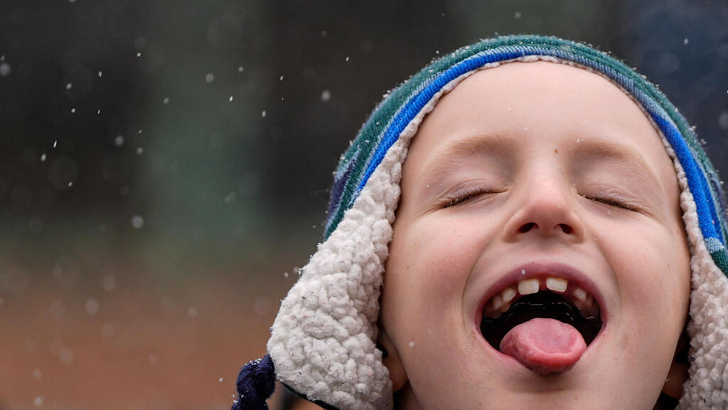 ילד תופס פתיתי שלג בלשונו במהלך מצעד יום שלושת המלכים השנתי ה־47 של מוזיאון אל מוזיאו דל באריו, 6 בינואר 2025, בניו יורק.
