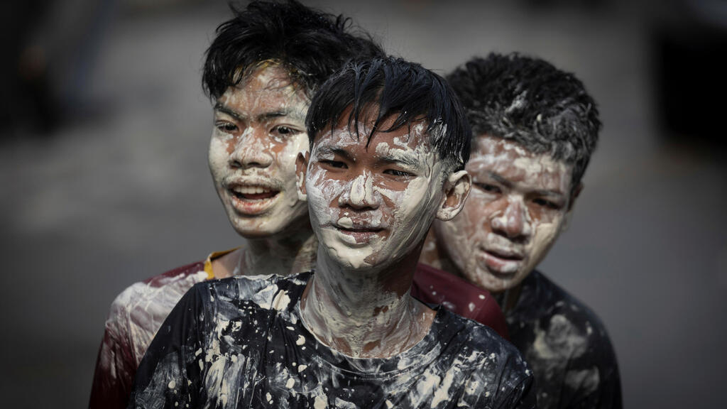 צעירים מורחים משחה אבקתית בשם דִין סוֹר פּוֹנְג, שלה מיוחסות סגולות של ברכה והגנה, כשהם משתתפים בפסטיבל המים סונגקראן לציון ראש השנה התאילנדי, במחוז פראצ’ינבורי שבמרכז תאילנד, 13 באפריל 2025.