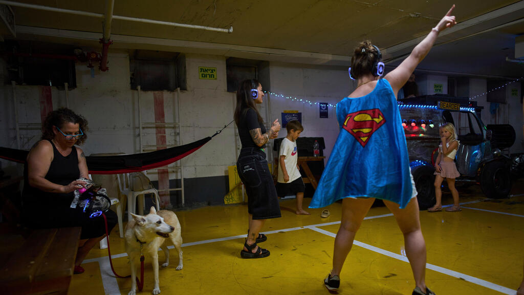 אנשים רוקדים במסיבת אוזניות בחניון תת-קרקעי המשמש מקלט מפני מתקפות טילים אפשריות מאיראן, בתל אביב, ישראל, 23 ביוני 2025