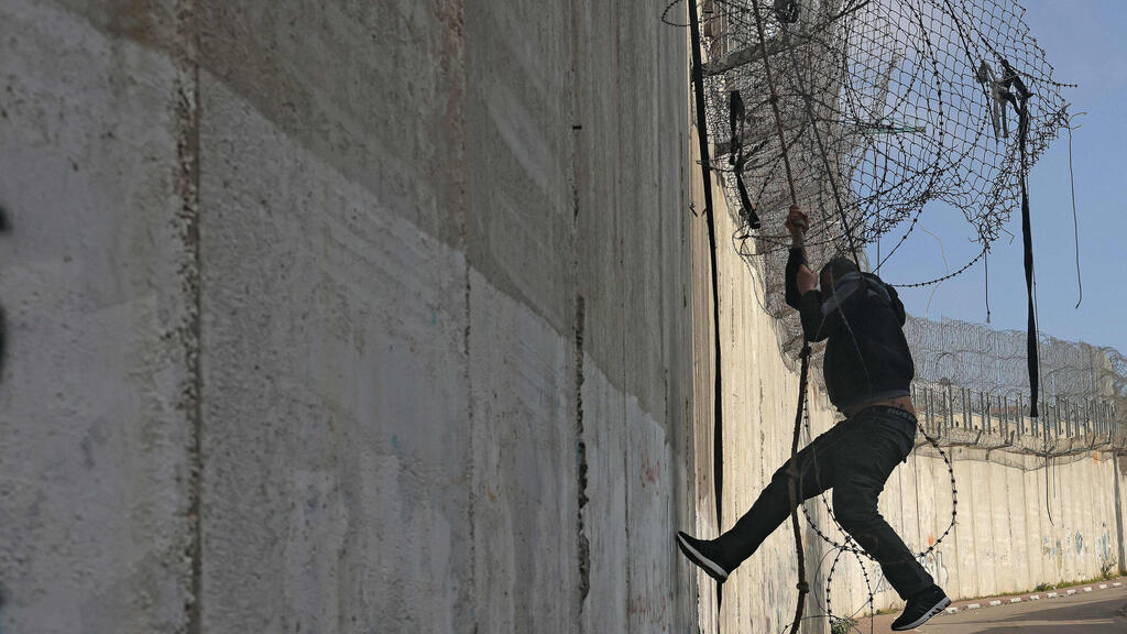 A Palestinian crosses the separation barrier in the Jerusalem area (Photo: AHMAD GHARABLI / AFP) ירושלים