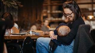 אישה מיניקה את בנה בבית קפה