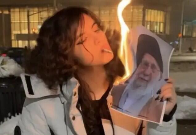 אישה איראנית שורפת את תמונתו של חמינאי עם סיגריה