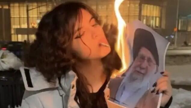 אישה איראנית שורפת את תמונתו של חמינאי עם סיגריה
