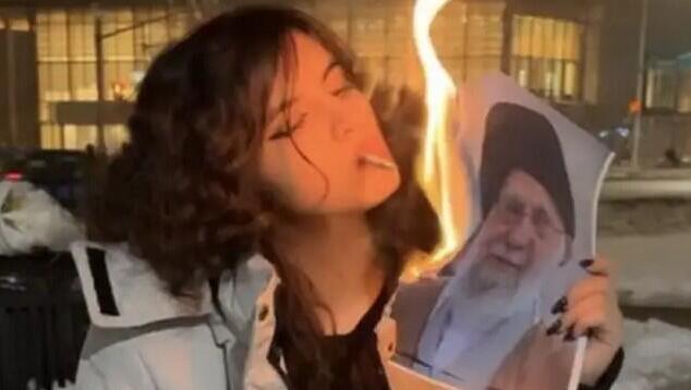 אישה איראנית שורפת את תמונתו של חמינאי עם סיגריה