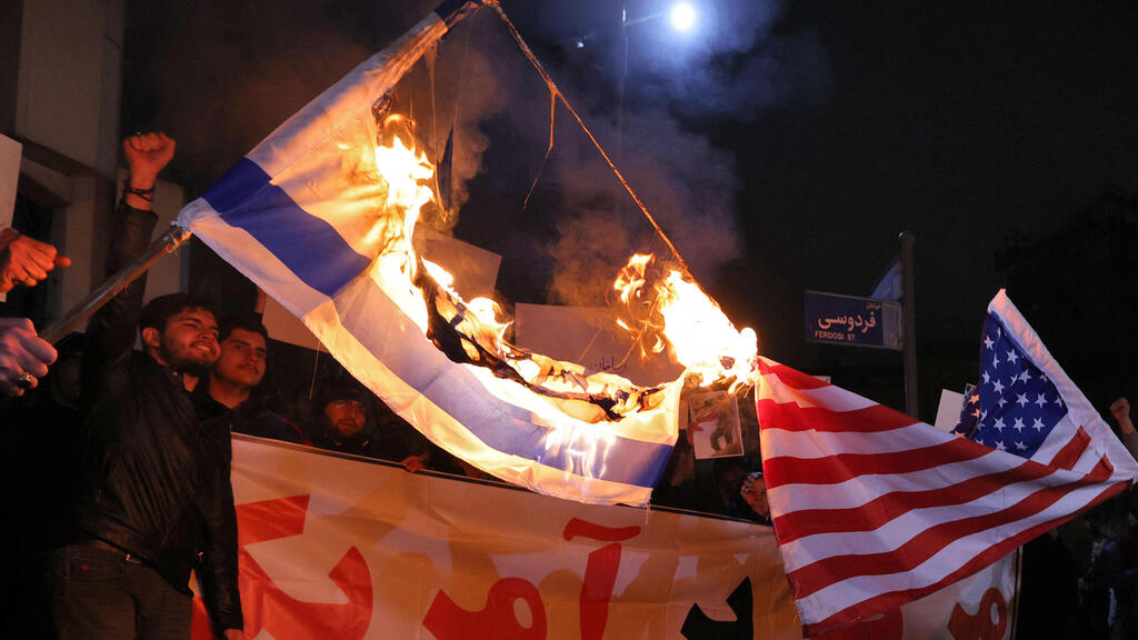 טהרן איראן אנשי מיליציה בסיג' הנאמנים למשטר שורפים דגלים של ישראל ו ארה"ב מול שגרירות בריטניה