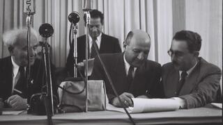 אליעזר קפלן חותם על מגילת העצמאות. מימינו משה שרת ומשמאלו דוד בן גוריון