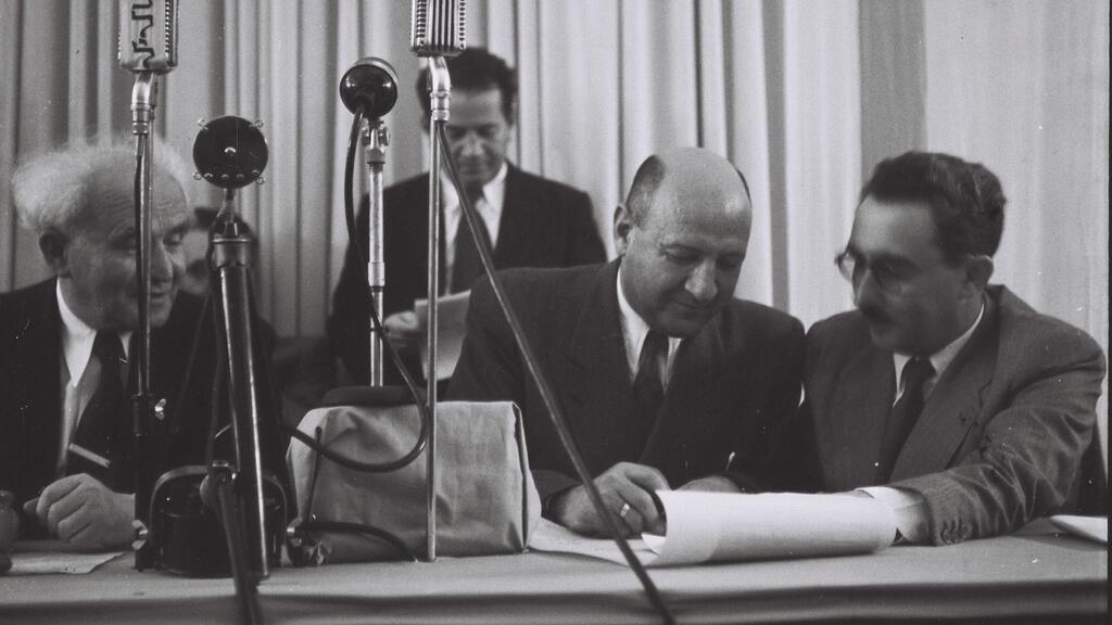 אליעזר קפלן חותם על מגילת העצמאות. מימינו משה שרת ומשמאלו דוד בן גוריון