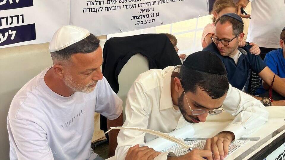 Kobi Samerano (left) at a ceremony marking the writing of a letter in a Torah scroll in memory of his son, Yonatan (Photo: Courtesy) קובי סמרנו (משמאל) במעמד כתיבת אות בספר התורה לזכר בנו, יונתן ז"ל